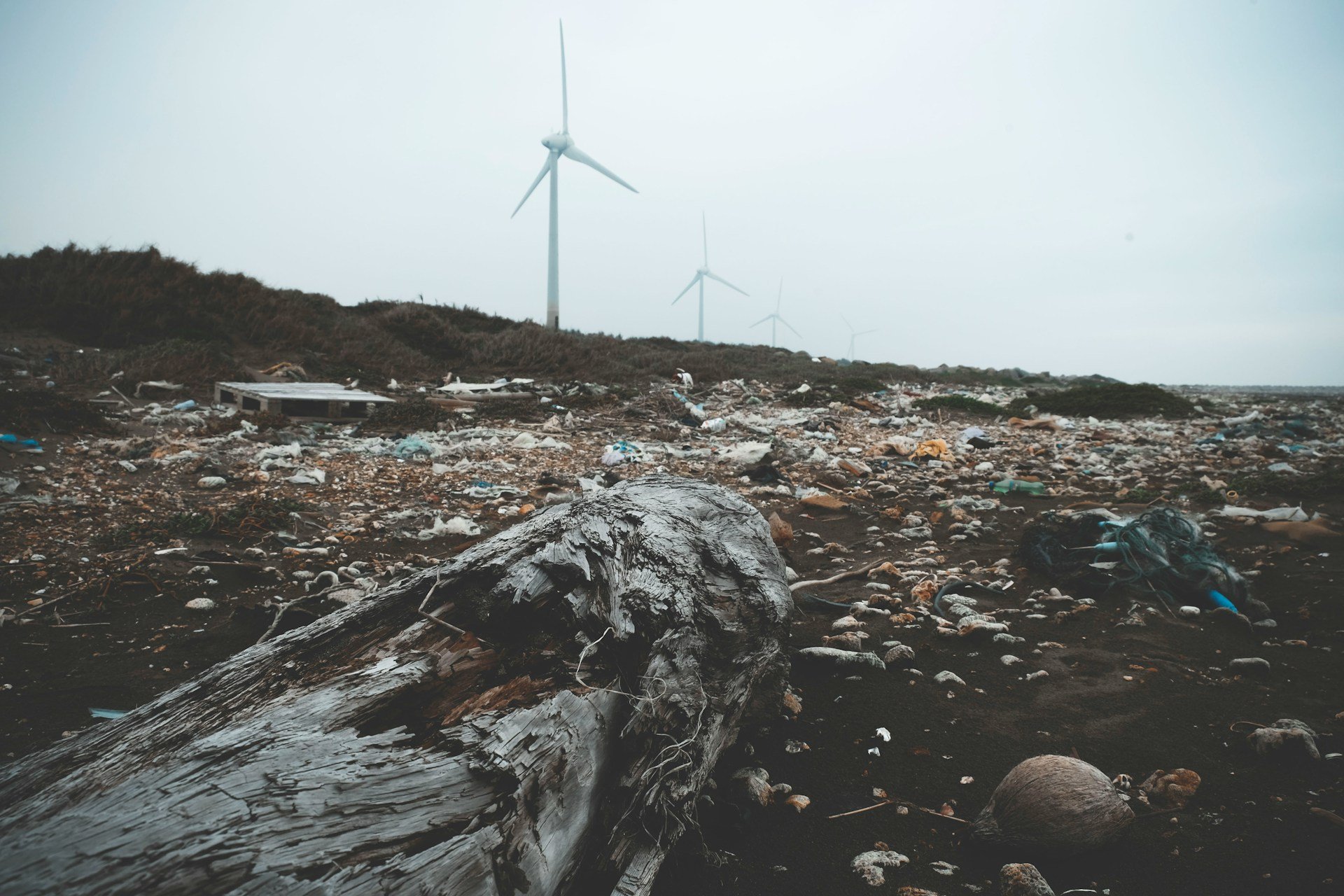 A beach in Guanyin District, Taiwan covered in plastic waste with a windmill in the background