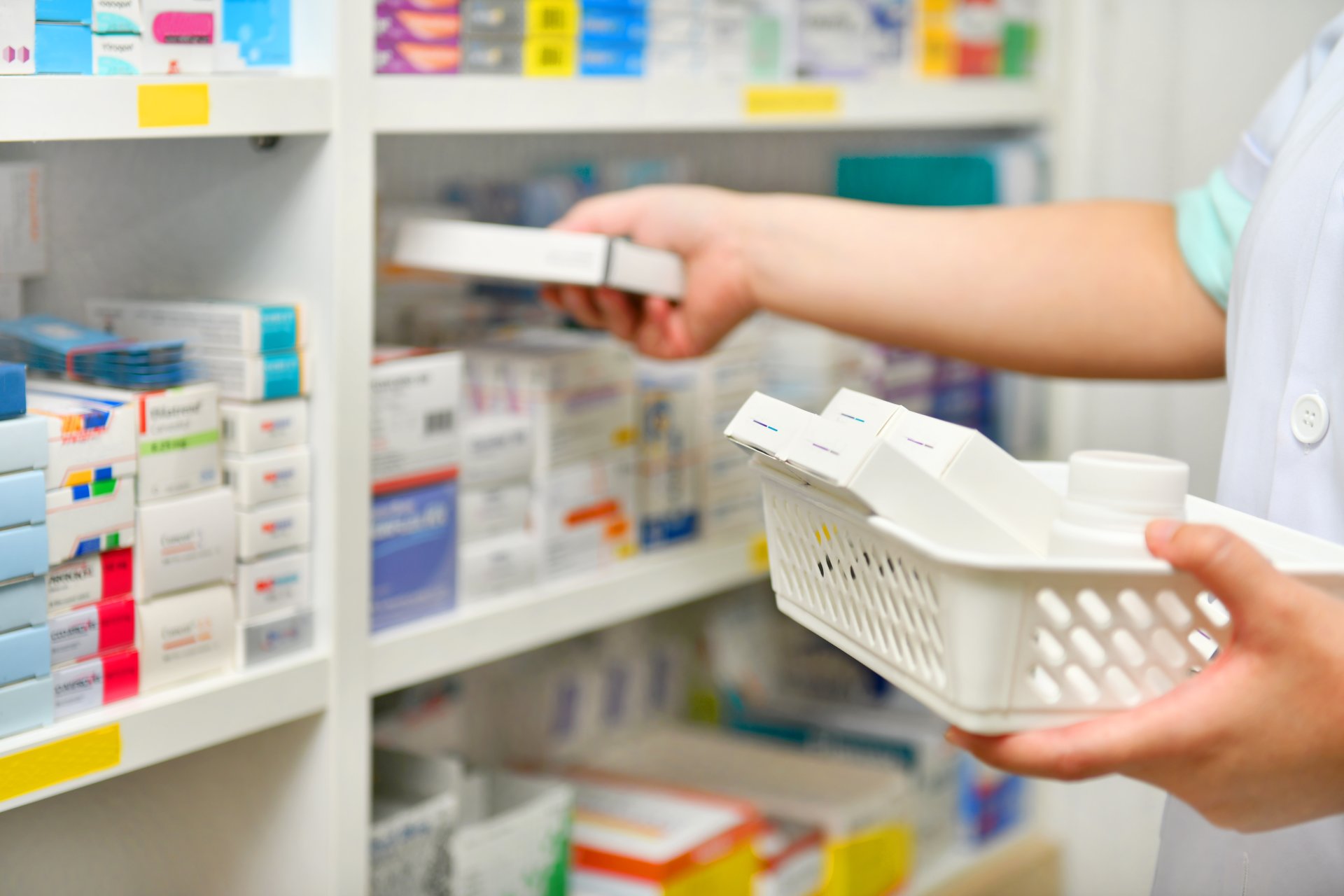 Shelf of pharmaceuticals being stocked by pharmacist 